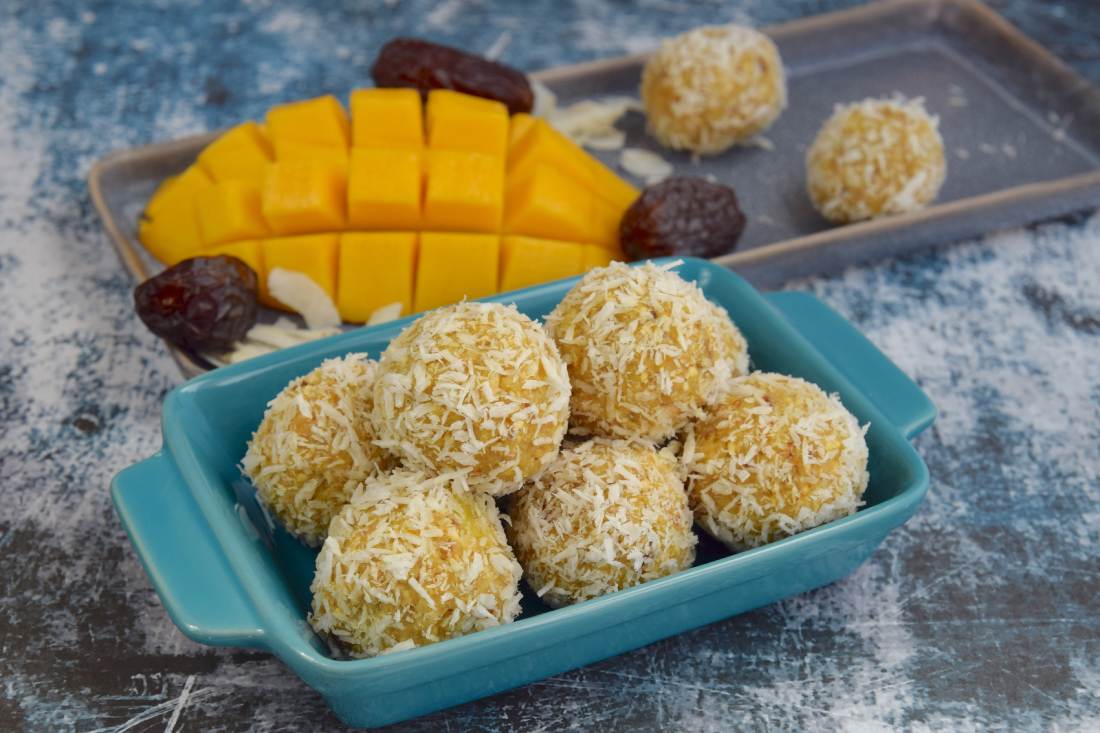 Shredded coconut mango energy balls on a tray