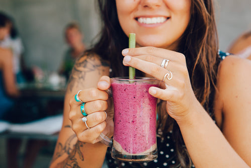 Young woman smiling and drinking a smoothie